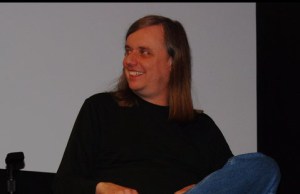 Photo of Steve Kurtz in panel discussion smiling in black jumper and blue jeans