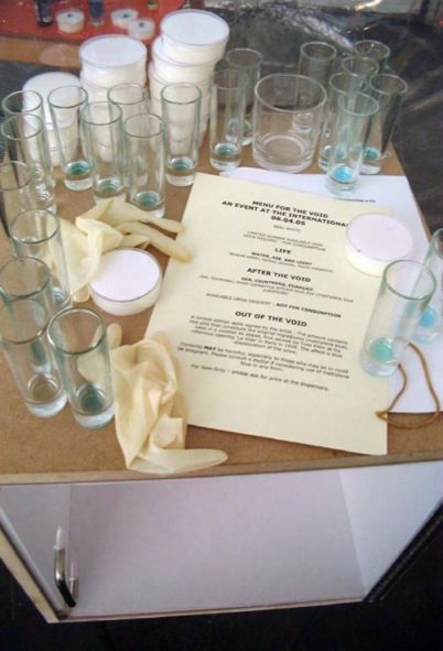 Glasses and dishes on a table, rubber gloves, a sheet of paper with 'Menu for the Void'
