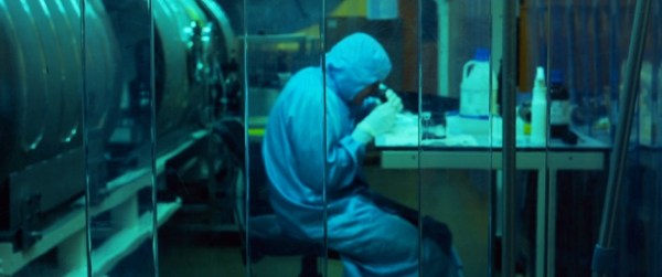 Image of scientist in clean room looking down microscope