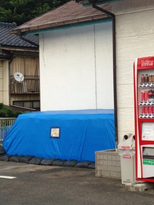 Blue covered pile outside shop with vending machine next to it