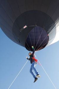 black balloon, person suspended, blue sky