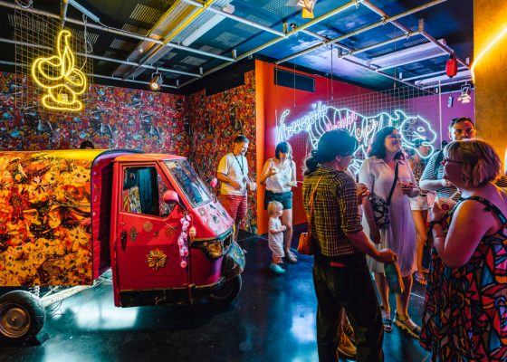 Groups of people talk within a visually rich, neon-bedecked installation.